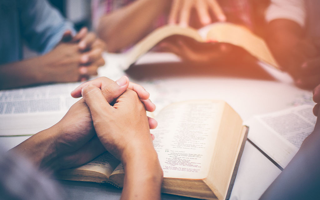 Praying hands on an open Bible
